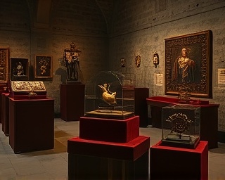 historical church relics, intriguing, displayed on velvet pedestals, photorealistic, situated in a dimly lit museum room with ancient stone walls, highly detailed, atmosphere of reverence and history, ultra high resolution, deep earthy tones, soft spotlighting, shot with an 85mm lens